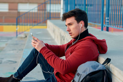 Young man using mobile phone while sitting outdoors