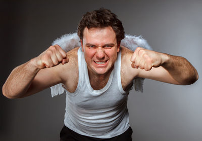 Portrait of man with arms raised against gray background