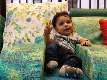 Portrait of cute boy sitting on bed at home