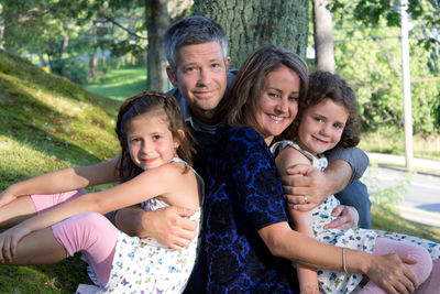 Cheerful family sitting by tree