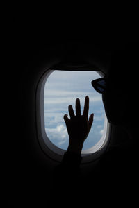 Silhouette of man looking through airplane window