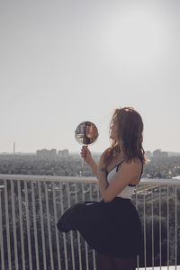 Woman looking at cityscape against clear sky
