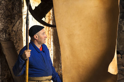 Worker looking at leather hanging in tannery