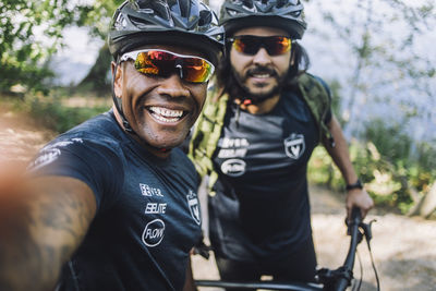 Happy male cyclist taking selfie with friend