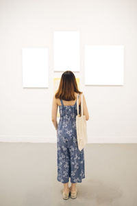 Rear view of woman standing against wall at museum