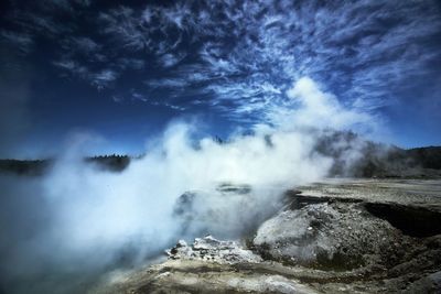 Steam emitting from hot spring against cloudy sky