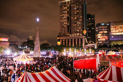 Crowd at illuminated city against sky at night