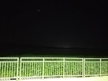 Fence on field against sky at night