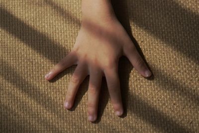 Low section of person touching shadow on carpet