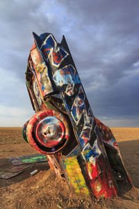 Close-up of rusty metal on field against sky