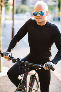 Smiling man with bicycle on road