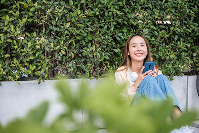 Portrait of young woman standing against plants