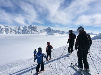 Rear view of people skiing on snowcapped mountains against sky