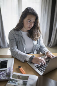 Young woman using phone while sitting on table