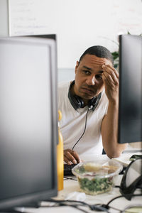 Worried male entrepreneur with head in hand sitting at desk in office