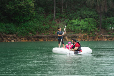 People on boat in river against trees