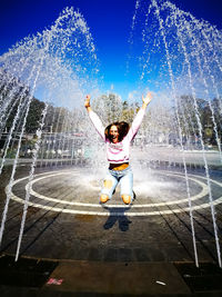 Happy young woman with jumping amidst fountain