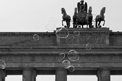 Low angle view of bubbles in mid-air against brandenburg gate