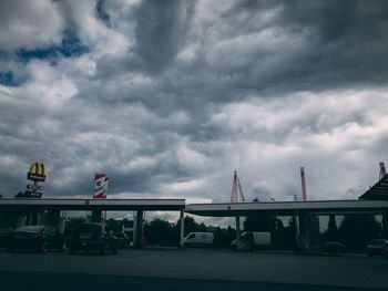 Cars on road against cloudy sky