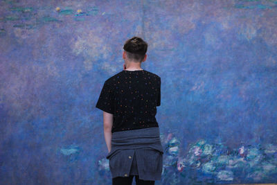 Rear view of man looking at painting