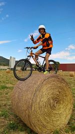 Man riding bicycle on field against sky