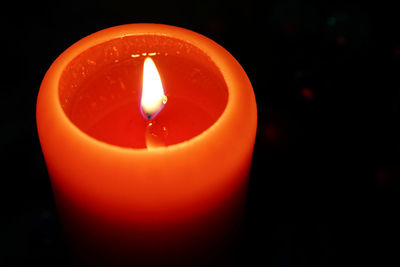 Close-up of lit candle against black background