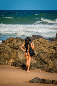 Rear view of woman standing on beach against clear sky