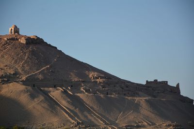 Scenic view of tombs of the nobles in aswan at sunset against clear sky