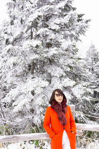 Portrait of woman standing on snow covered tree