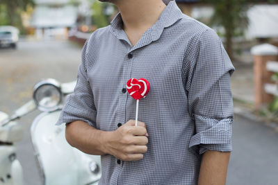 Midsection of man making heart shape lollipop