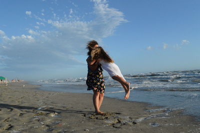 Woman lifting girl on beach