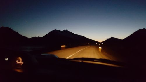 Cars on road against sky at sunset