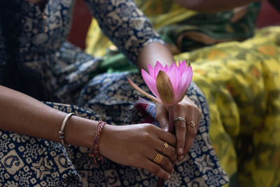 Woman hands holding beautiful lotus flower hand holding pink lotus flower on black background