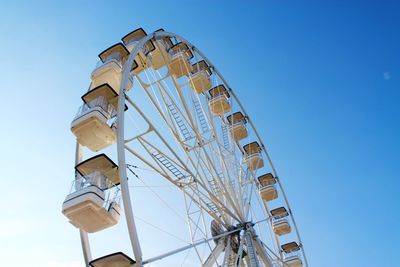 Low angle view of ferris wheel against clear blue sky