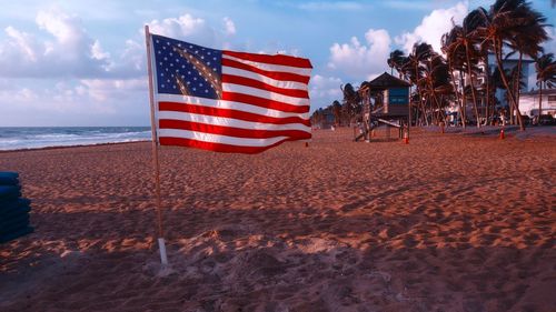 American  flag on beach against sky