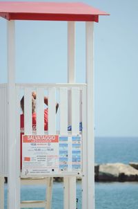 Information sign by sea against sky