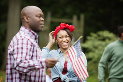 Happy woman looking at man holding american flag in backyard