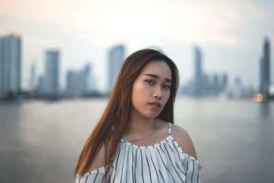 Portrait of beautiful woman standing against cityscape in city
