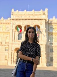 Portrait of beautiful woman standing against building in city