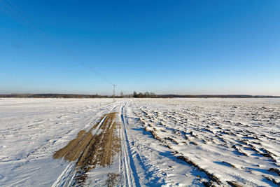 Snow covered field against clear blue sky