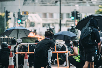 Rear view of people on street in rain
