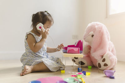 Cute girl playing with toy sitting on floor at home
