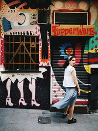 Full length of woman standing against multi colored building