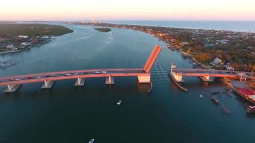 High angle view of illuminated bridge over river in city at sunset