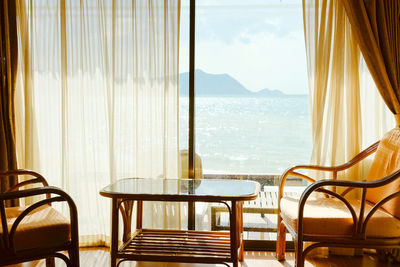 Chairs and table in room against sea