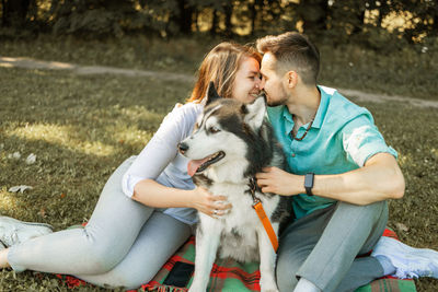 Portrait of young couple having fun with their husky dog in park