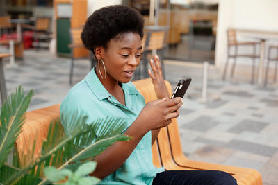 Young woman using mobile phone while sitting at outdoor cafe