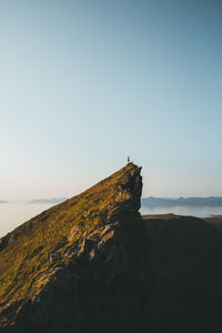 Mid distant view of man standing on cliff against sky