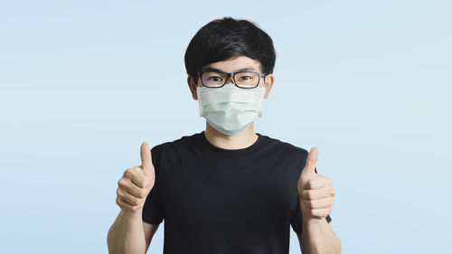 Portrait of young man standing against blue background