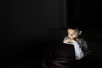 Boy watching scary movie on laptop at home